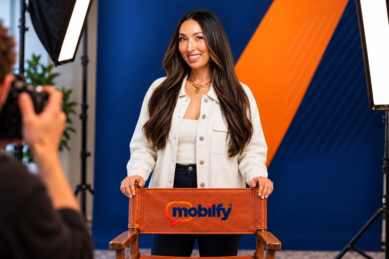 Pauletta Denning in a studio portrait, standing behind a leather director’s chair embroidered with the Mobilfy logo